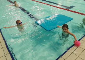 Dzieci pływają w basenie.